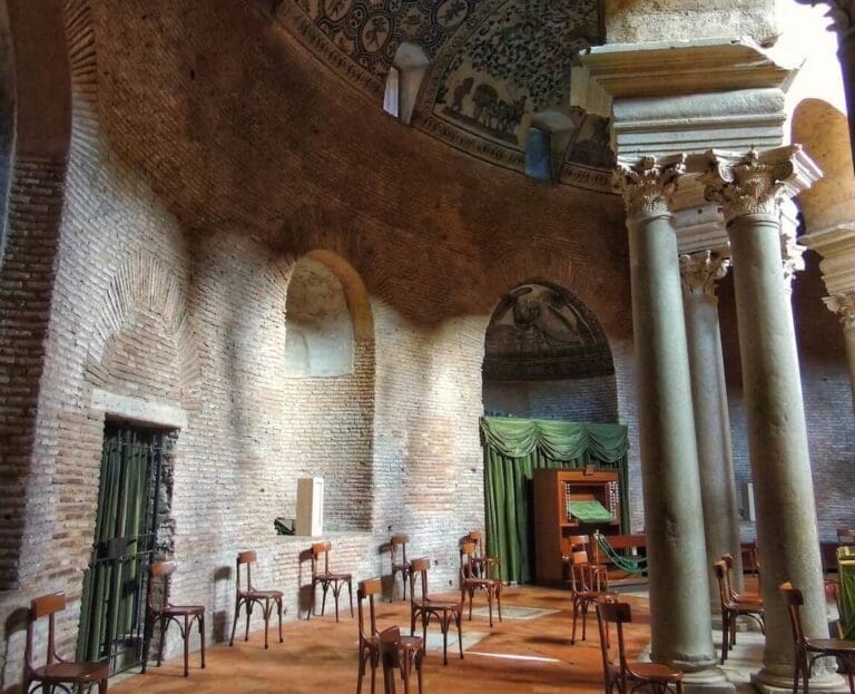 View of the interior of santa constanza with columns chairs and dappled light