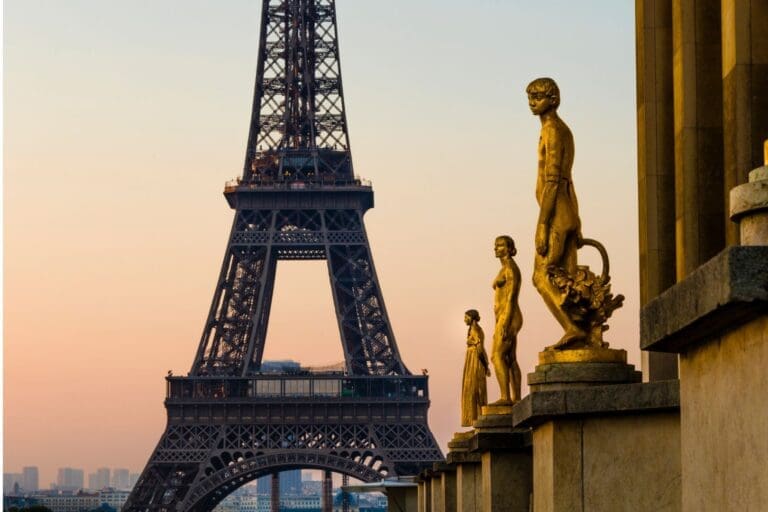 eiffel tower at dusk with sculptures in foreground