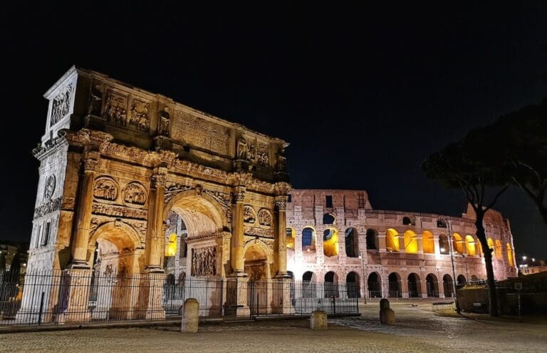 View of the illuminated Arch of Constantine at Night with the Colosseum in the background