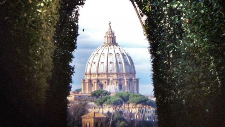 View through the keyhole of the Priory of the Knights of Malta in Rome showing the dome of St. Peter's Basilica framed through the bushes at the end of an avenue