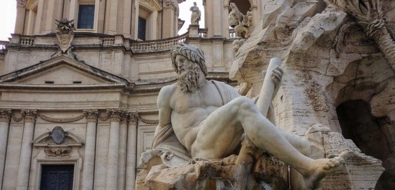 View of the statue representing the River Ganges on the fountain of the Four River in Piazza Navona Rome with the church of St Agnes in Agone in the background