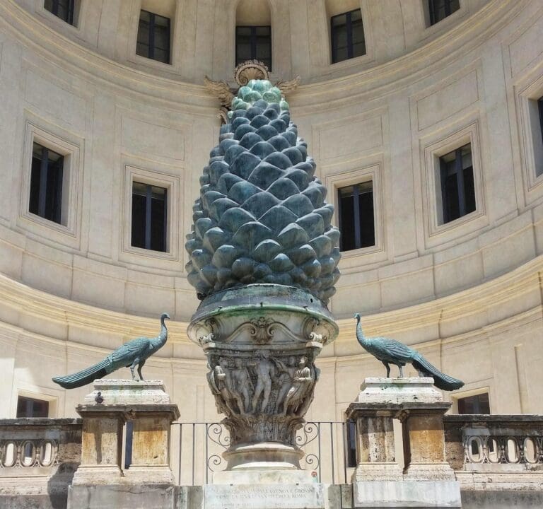 Photo of the Broze Pinecone flanked by two bronze peacocks in the Pinecone Courtyard