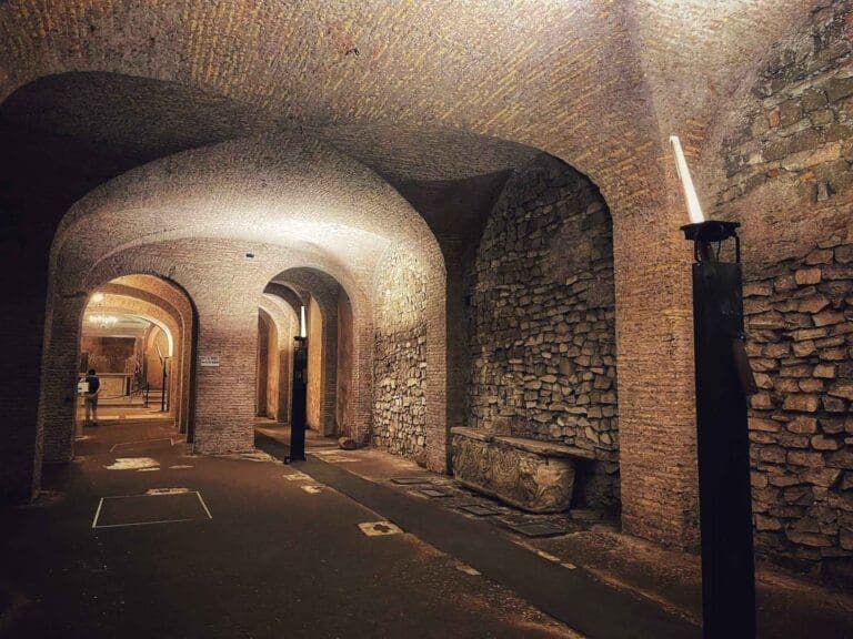 San Clemente lower underground basilica in Rome showing brick construction and vaults dimly lit with a view to the altar in the background