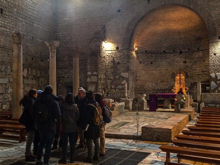 Tour group in the underground basilica in the catacombs of Domitilla in Rome