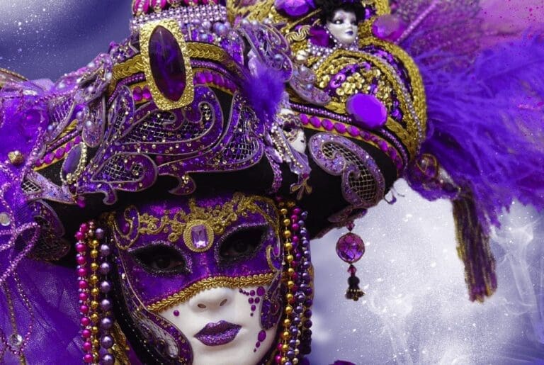 Vivid purple feminine Carnival mask for the Venetian Carnival adorned with purple jewels and purple feather plumes