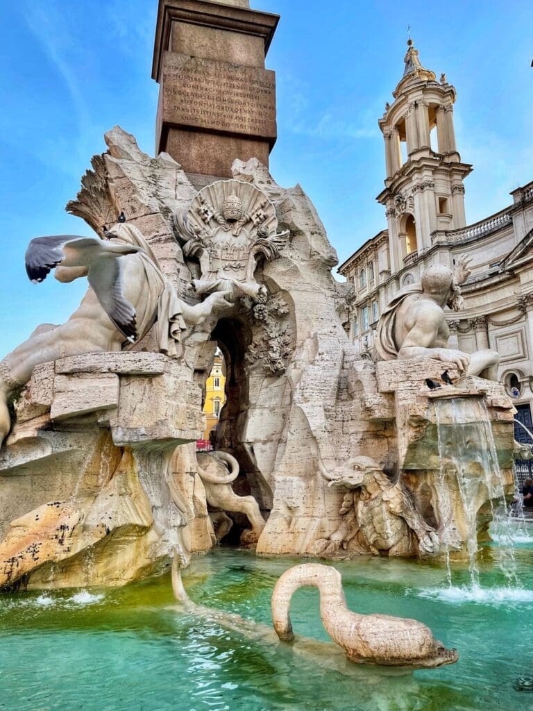 View of the statue representing the River Ganges on the fountain of the Four River in Piazza Navona Rome with the church of St Agnes in Agone in the background